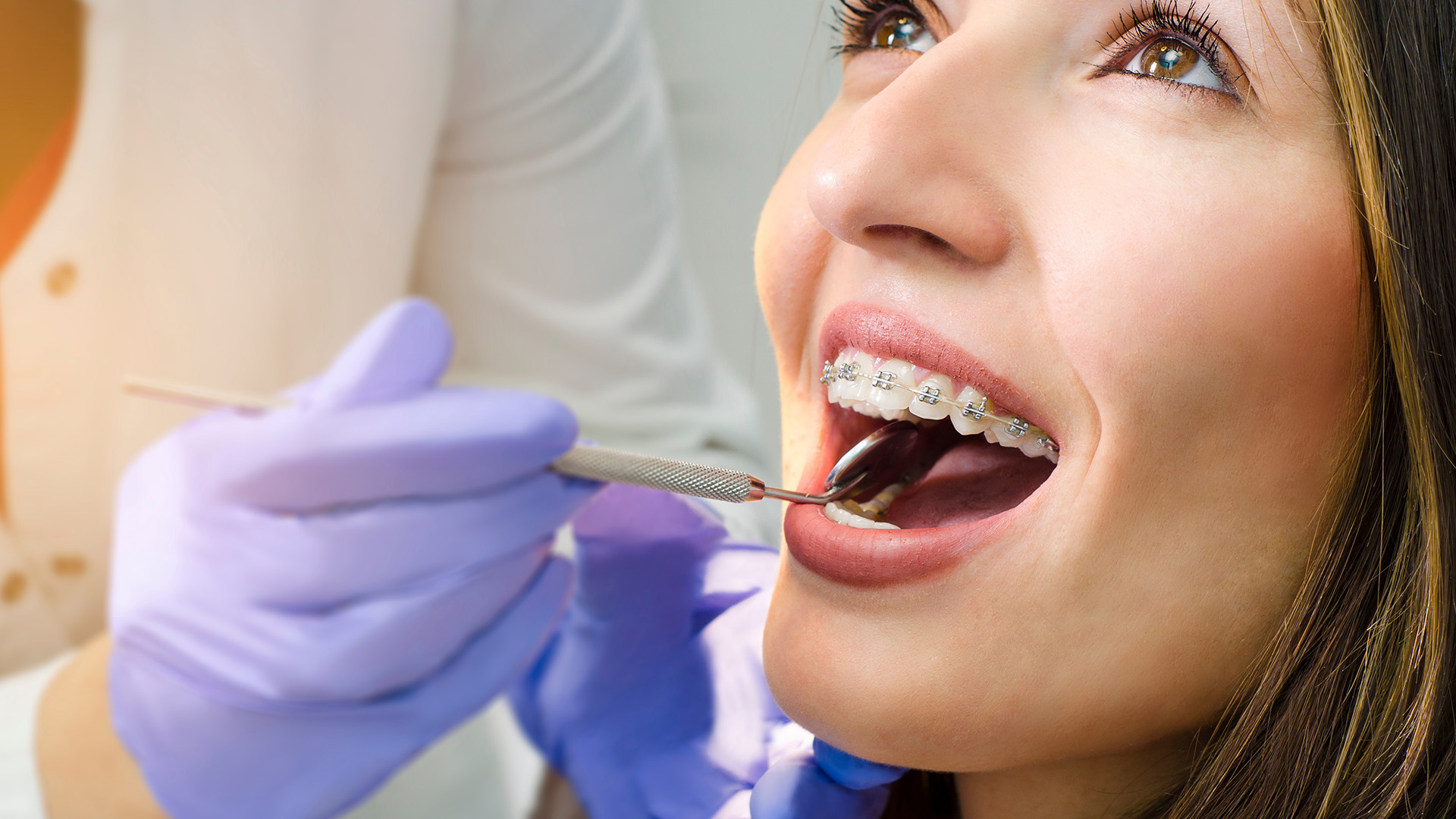 Woman receiving dental treatment with a dentist using a drill.