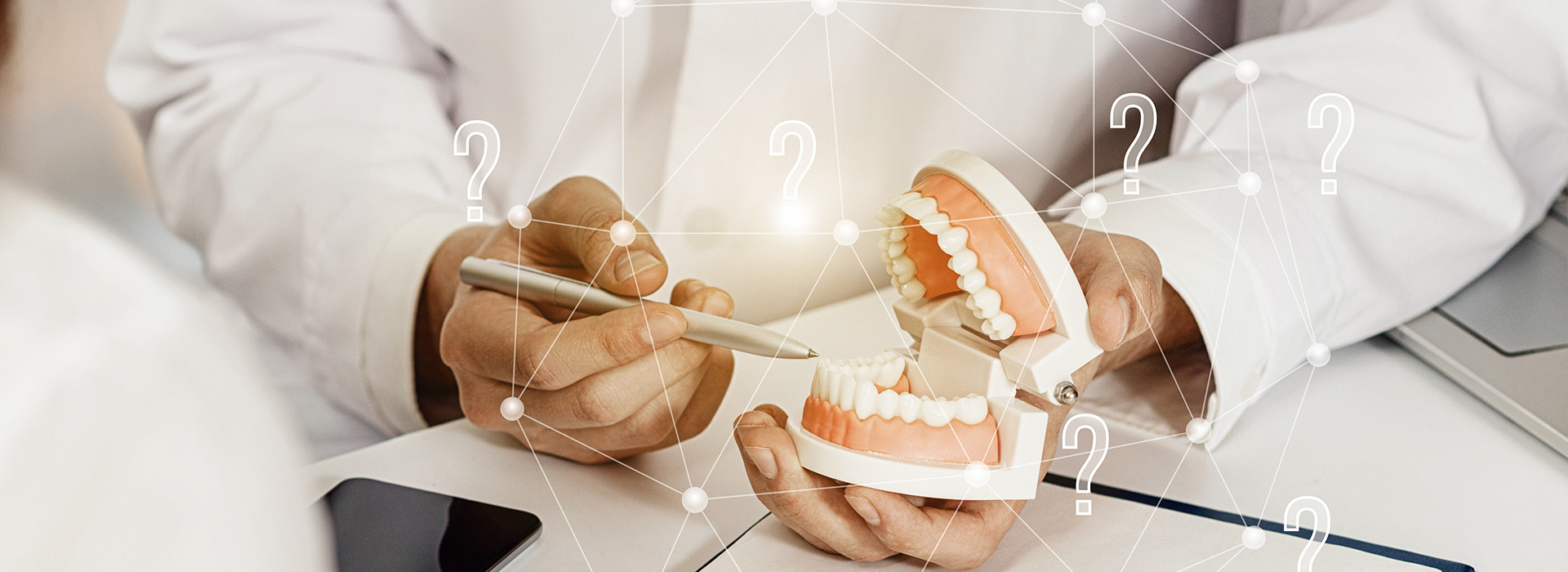 An image of a person s hand holding a model of a human tooth, with a digital interface displaying dental implant options and a dental professional in the background.