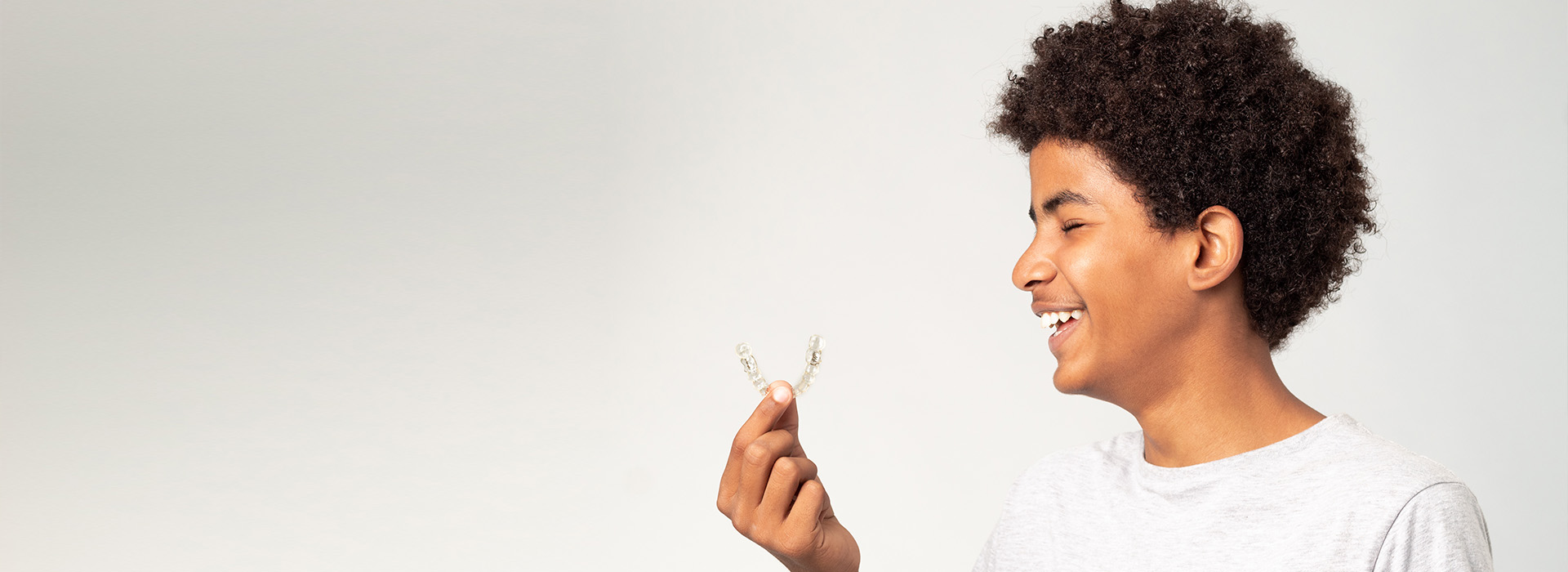 A person holding a flower in front of their face, smiling at the camera.