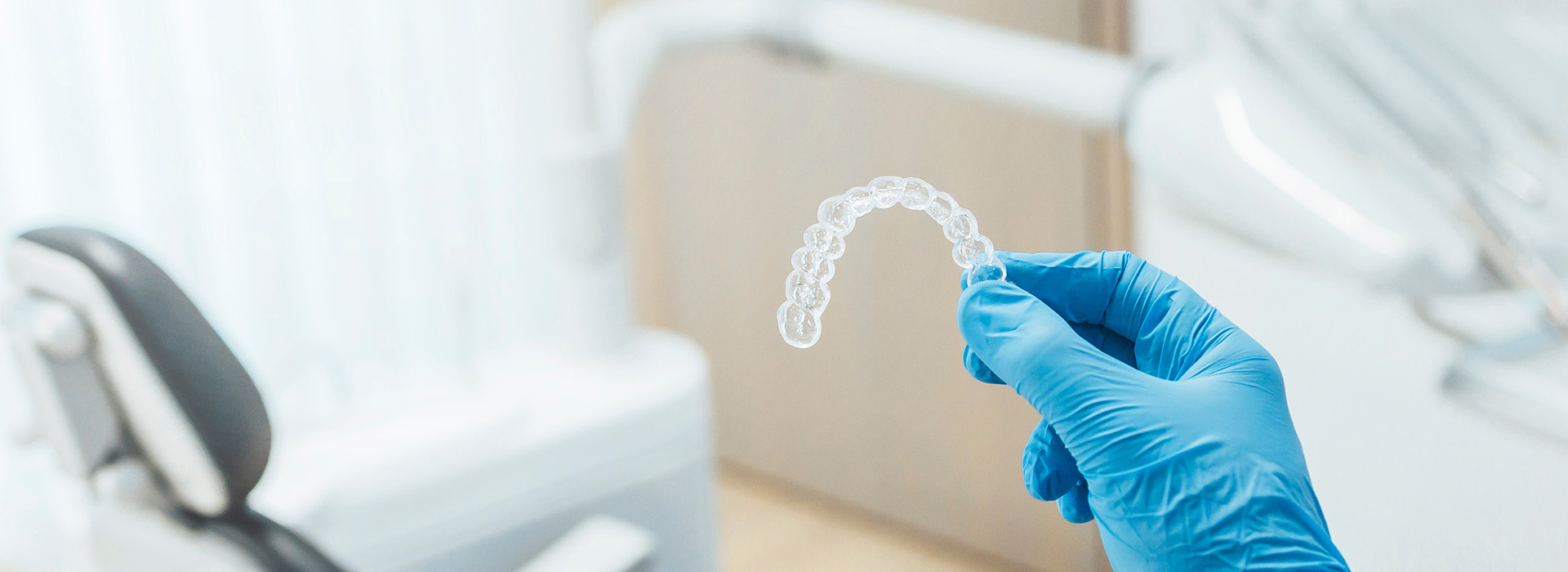 Hand holding a transparent dental impression in a clinical setting.