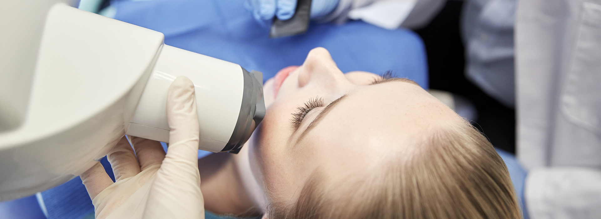 A person receiving dental care, with a dentist using a magnifying loupe to examine their teeth.