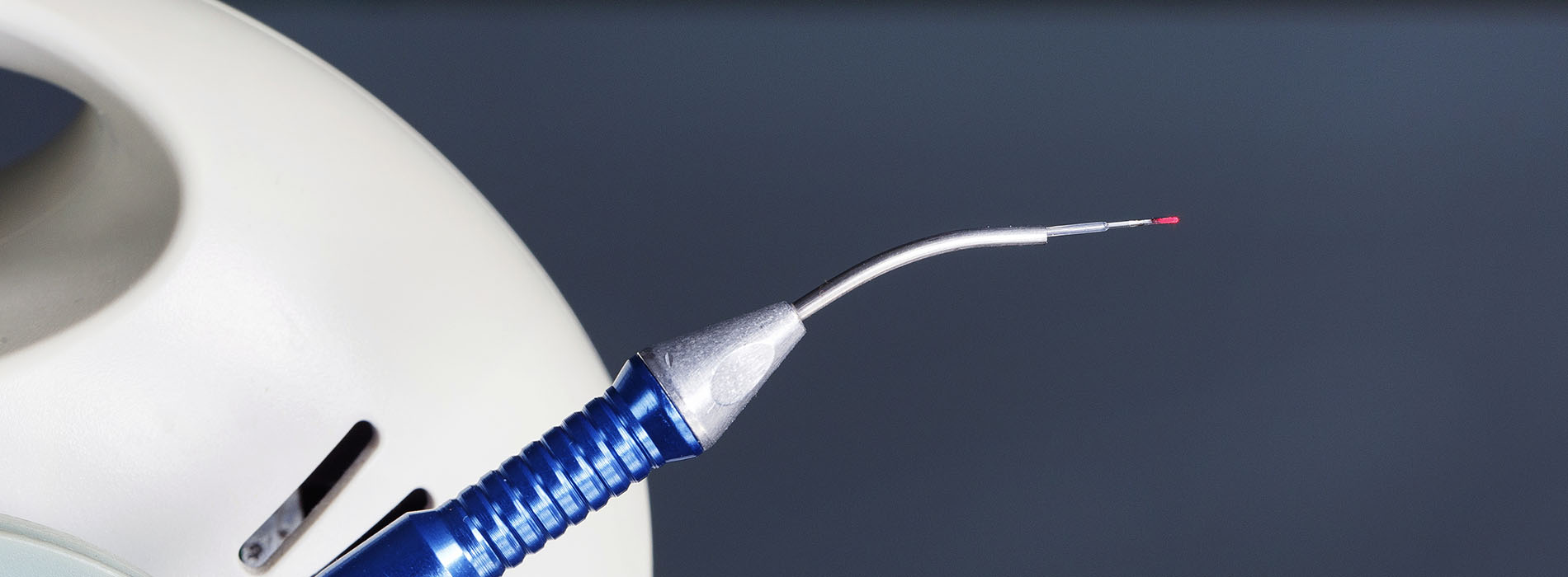 The image shows a close-up of a medical device with a needle and thread, suggesting a surgical or medical context.