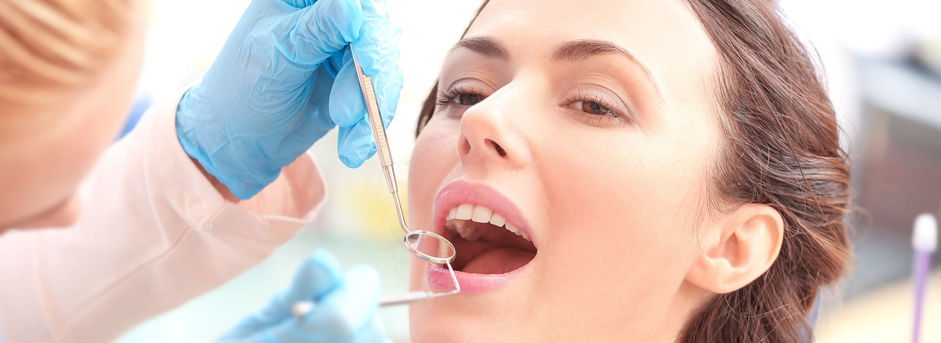 A dental hygienist is performing a teeth cleaning procedure on a patient s mouth.