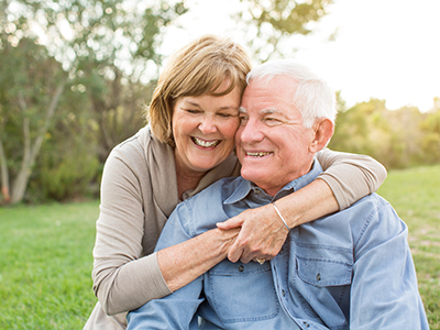 A man and woman, likely an older couple, are hugging each other closely.