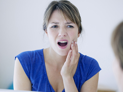 Woman with hand on face, looking distressed or in pain.