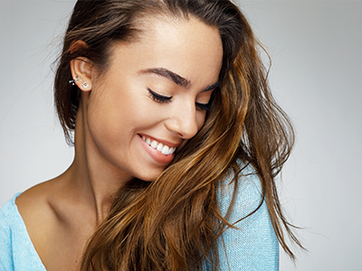 A woman with long hair, smiling and looking to her right.