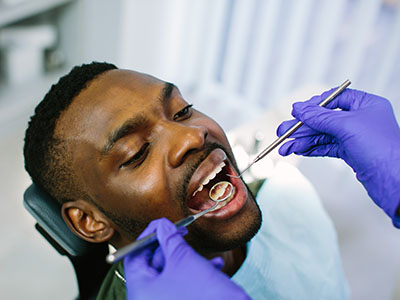 A person in a dental chair receiving dental care, with a dental professional performing the procedure.