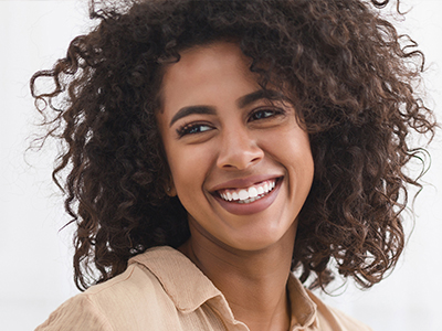 The image shows a person with curly hair, smiling and looking directly at the camera.